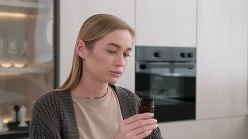 Woman Taking Pills with Water in Kitchen
