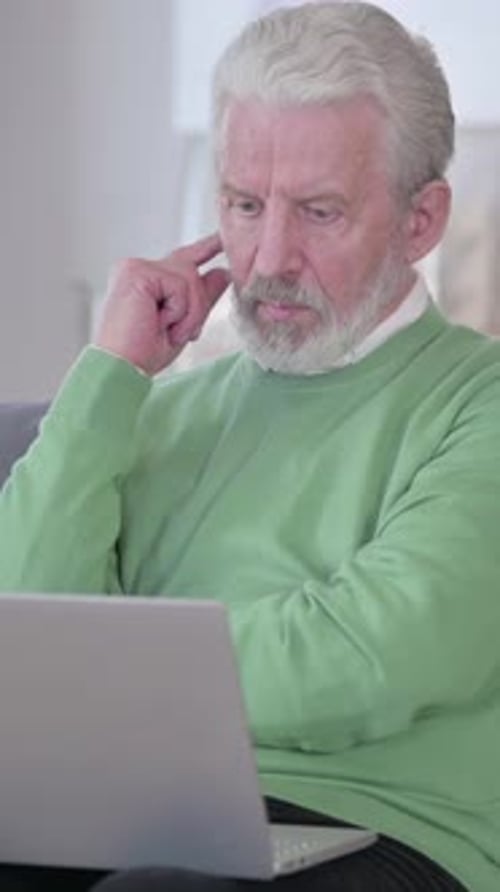 Senior Man Contemplating While Using Laptop Indoors
