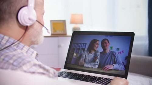 Senior Man Video Chatting With Young Couple on Laptop