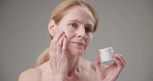 Woman Applying Cream to Face for Skincare Routine