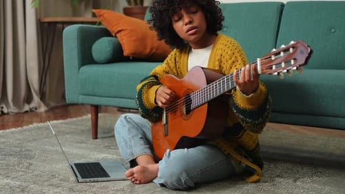 Young Woman Playing Guitar at Home