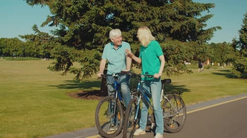 Joyful Loving Retired Couple on Bicycles Bonding and Enjoying Leisure in Park