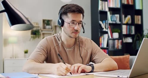 Man Writing Notes While Working From Home