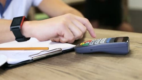 A businessman puts a smartphone to the terminal making a successful contactless payment.