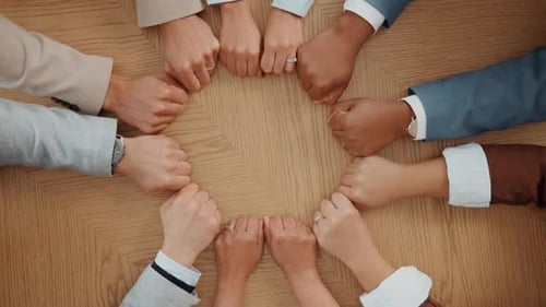 Business people, hands and fist in circle for teamwork, collaboration or synergy at table