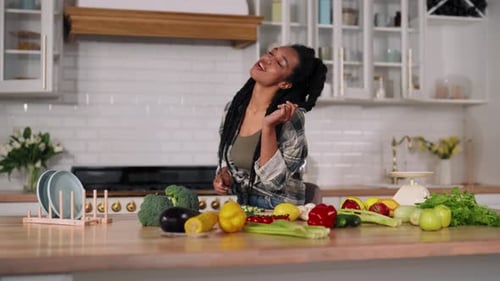 Woman Chopping and Tasting Vegetables in Kitchen