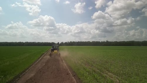 Grader works with tractor and levelling the field road