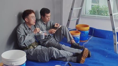 Repairmen Having Lunch after Painting Walls at Construction Site