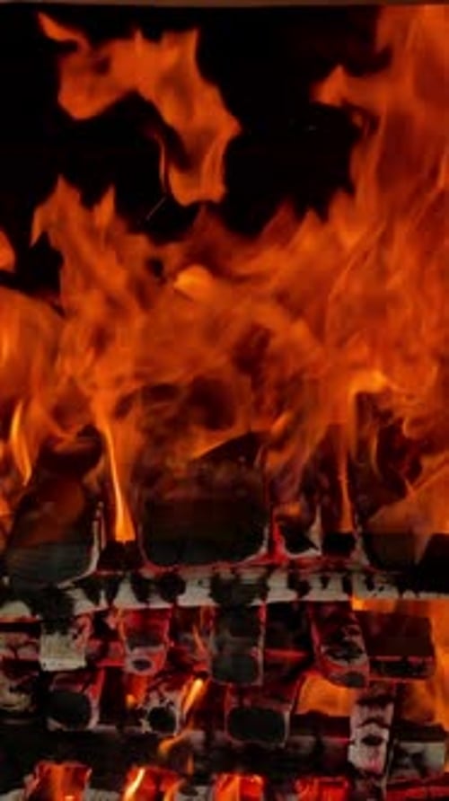 Logs carefully stacked in a pile burn with good flame. Wood burning for barbeque. Close up.