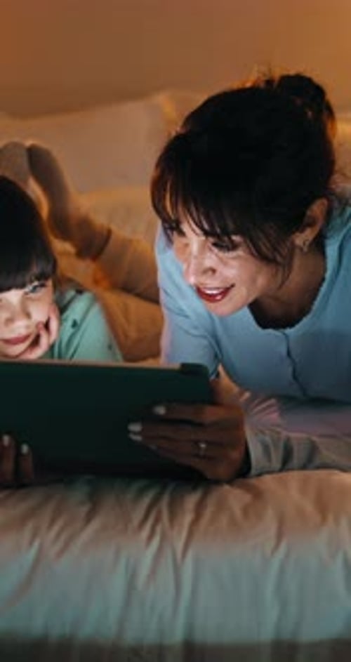 Night, mother and girl in bedroom with tablet for online streaming, internet or cartoons together