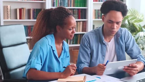 Young African American Man and Woman Brainstorming Together Sits at Office Table