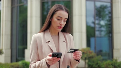 Young Woman Uses Phone with Credit Card