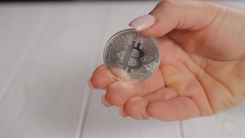 Hand Holding a Silver Bitcoin on White Background