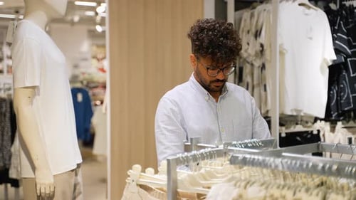 Arabic Customer Choosing Clothes in Fashion Store with Discount