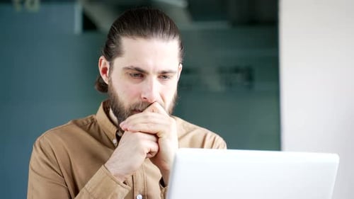 Man Thinking at Laptop in Office Setting