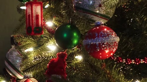 Close-up of beautifully decorated Christmas tree ornaments, featuring red and green baubles, twinkli