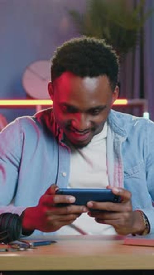 Excited Young Man Playing Video Game on Smartphone