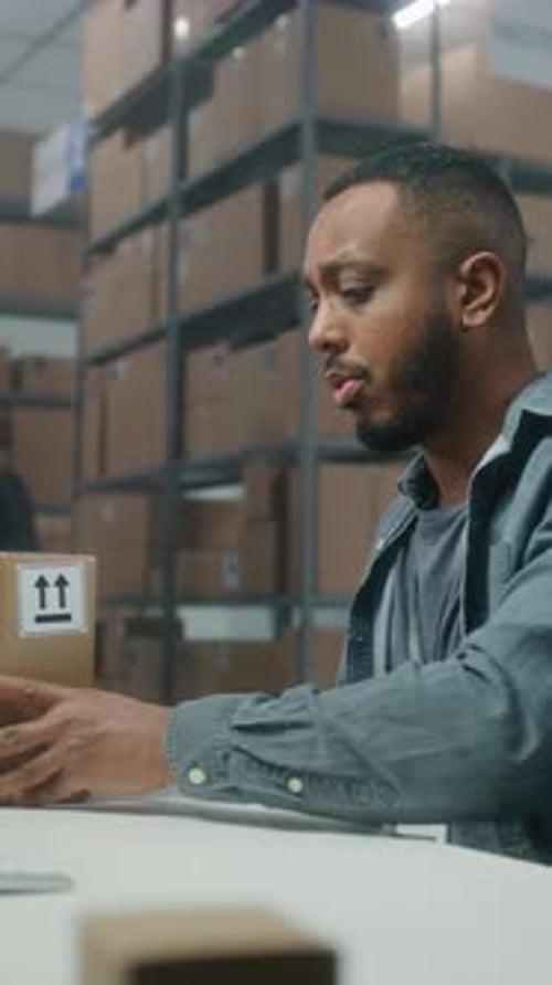 African American Warehouse Clerk Scans Parcel with Barcode Scanner Uses Computer