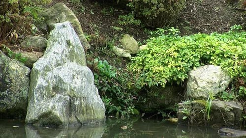 Decorative rocks on edge of pond in autumn.