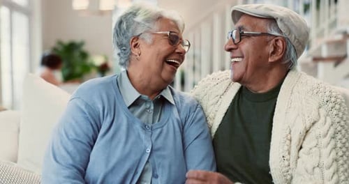 Smiling Senior Couple Laughing Together on Couch Indoors