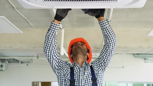 Man Repairing Air Conditioner in Office Space