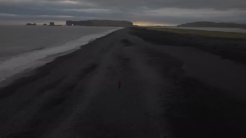 Solitary Figure on Iceland's Black Sand Beach