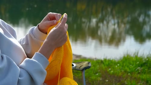 Woman's Hands Knitting Outdoors By a Lake