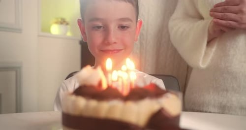 Child Blows Out Candles on Birthday Cake