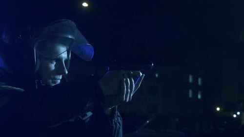 Police Officer in Helmet Holding Gun at Night