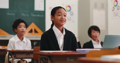 Students in Uniforms Sitting at Desks in Classroom