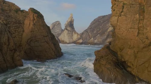Raues Meer an einem abgelegenen Sandstrand, umgeben von Klippen bei Sonnenuntergang. Drohne Dolly im Schuss. Strand Ursa, Po