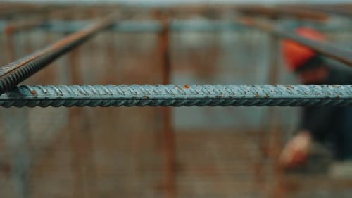 Steel Rebar Grid with Worker in Background at Construction Site
