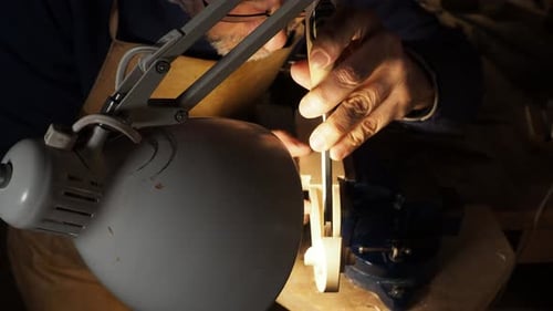 Man Carving Violin Neck in Woodworking Workshop