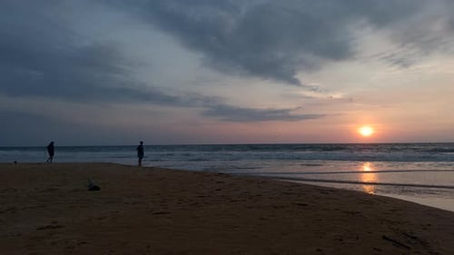Dramatisch Sonnenaufgang am bewölkten Himmel, Action, gewellter Sand, Meeresschuh und ein Paar, das sich am neuen Tag trifft