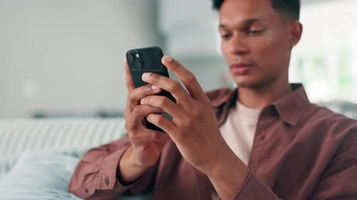Young Adult Relaxing With Smartphone, Smiling Indoors