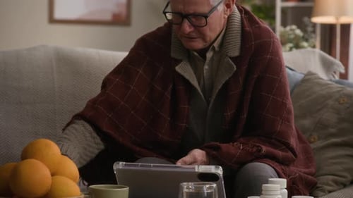 Senior Man Covered in Blanket Examining Medication