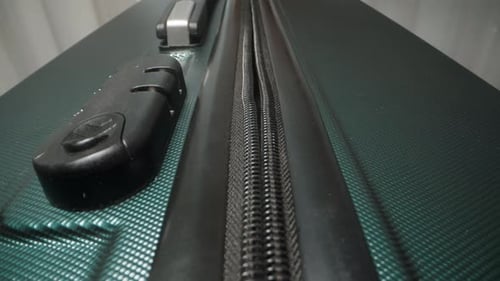 Fingers fasten the zipper pulls into the suitcase's combination lock, ensuring the luggage.