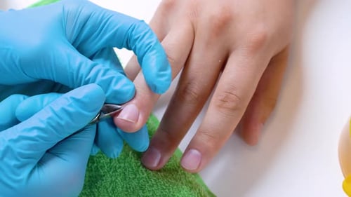 Close-up of the client’s hand and the nail master in processing nails in gloves will raise a cuticle