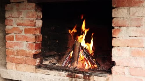 Burning Firewood in Brick Fireplace at Night