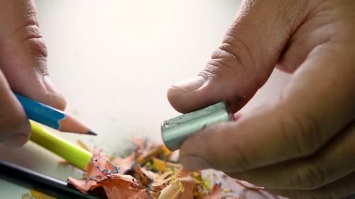 Footage of hands slowly sharpening a pencil and some coloured pencils with a Wedge Pencil Sharpener.
