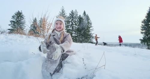 Mädchen genießt die Winterzeit. Fröhliches süßes Mädchen spielt mit dem Schnee in einem Park und wirft ihn ins Auto