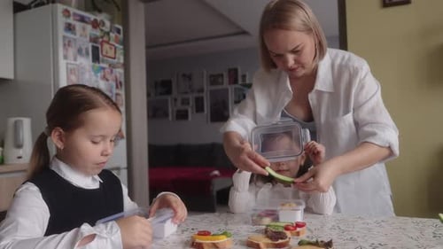 Mother Preparing School Lunch for Her Daughters in the Kitchen