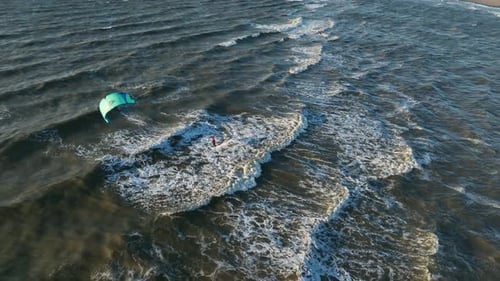Wide shot of a kitesurfer playing in the waves of