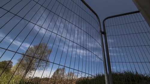 Zeitraffer von Wolken, die durch einen Bauzaun ziehen