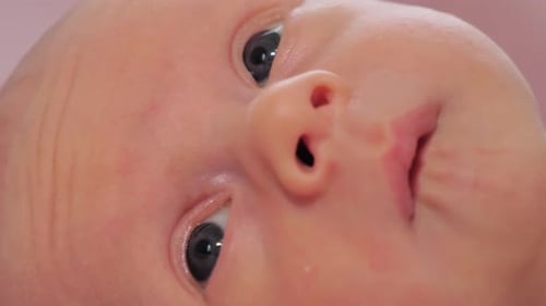 Super Closeup of Newborn Baby Face Caucasian Child Laying on the Bed and Looking Around Slow Motion