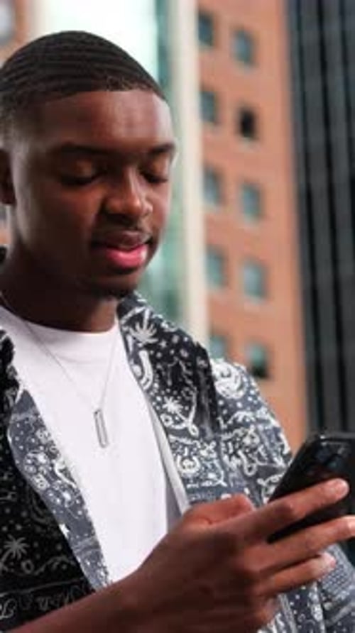 African American Person Using Smartphone with Vibrant Modern City Backdrop Vertical Video