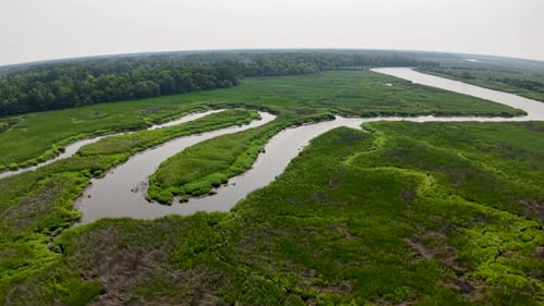 Aerial drone footage capturing a marshland with winding river channels and green islands of grass