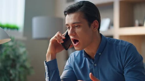 Concentrated Young Man Talking on Phone Indoors
