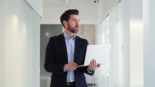 Dedicated Businessman is Working Diligently on Laptop in the Office Corridor