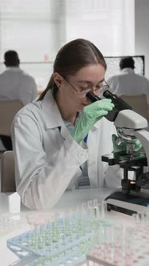 Female Scientist Using Microscope in Medical Research Lab